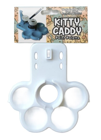 White paw-shaped paint palette with 'Kitty Caddy' packaging in the background